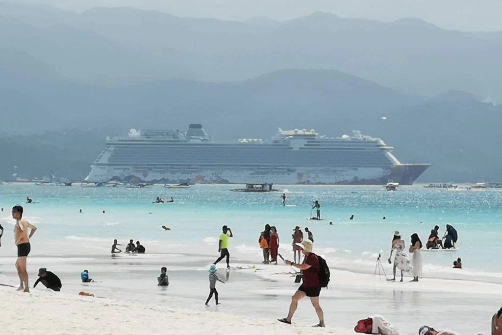 Boracay white beach with tourist enjoying the beach and the cruise ship behind