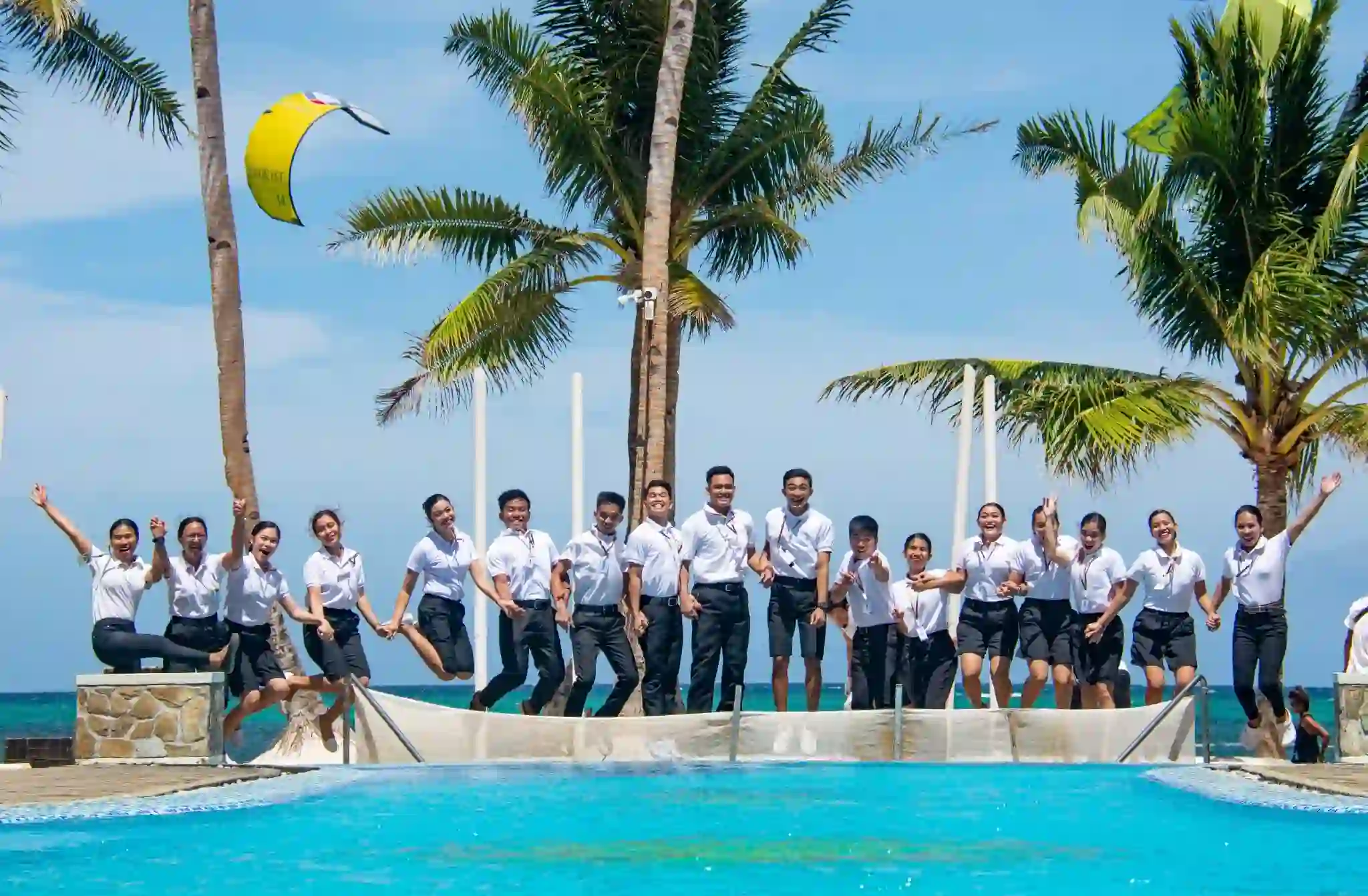 OJT students poses for a picture with the beach and coconut trees behind
